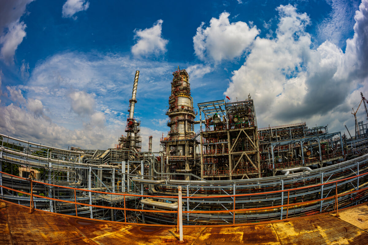 "Petrochemical oil refinery plant with industrial columns and pipelines under a clear blue sky"